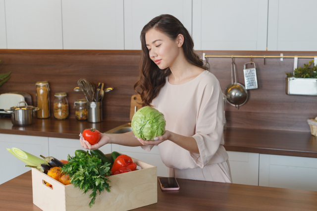 キッチンで野菜を持つ外国人の写真